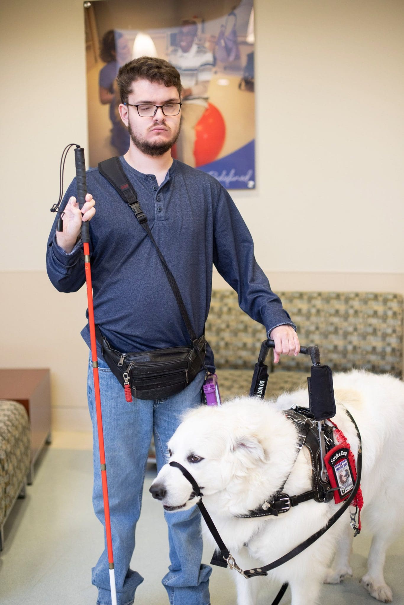 Young man with Intellectual and Developmental Disabilities (IDD) and visual impairment stands with his service dog at sensory-friendly healthcare clinic ready to receive patient-centered care.