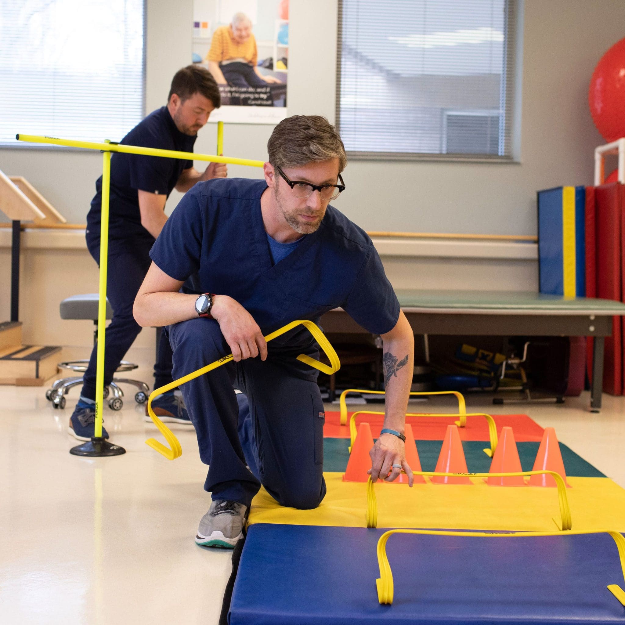 Two Occupational therapists setting up a sensory-friendly obstacle course for a patient with intellectual and developmental disabilities (IDD) to improve mobility, coordination, and daily living skills.